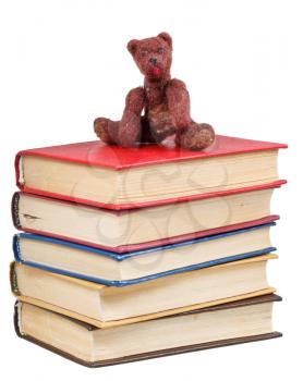 felt soft toy bear sits on stack of books isolated on white background