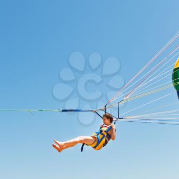 girl parasailing on parachute in blue sky in summer day