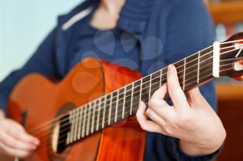 girl playing classical acoustic guitar close up