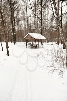 snow covered wooden pavilion in urban park in winter
