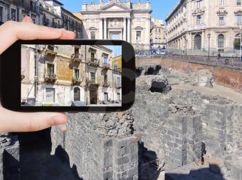 travel concept - tourist takes picture of facade of urban house in center of Catania, Sicily, Italy on smartphone,
