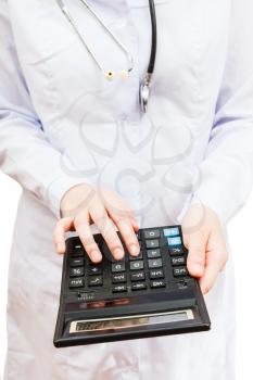physician calculates the cost of treatment on calculator
