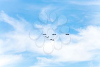 flight of military fighter planes in white clouds in blue sky