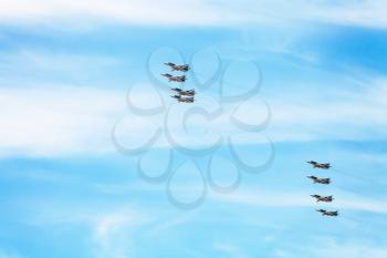 flight of military battleplane aircrafts in white clouds in blue sky