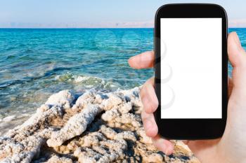 travel concept - tourist photograph crystalline coastline of Dead Sea, Jordan on tablet pc with cut out screen with blank place for advertising logo