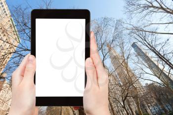 travel concept - tourist photograph skyscrapers and bare trees in New York in winter on tablet pc with cut out screen with blank place for advertising logo