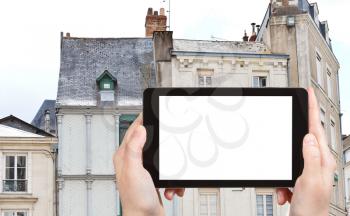 travel concept - tourist photograph facades of medieval half-timbered urban houses in Angers city, France on tablet pc with cut out screen with blank place for advertising logo