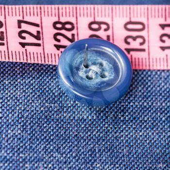 attaching of button to blue silk fabric by needle close up