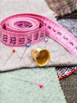 dressmaking still life - pink measuring tape, pins, thimble on tissue