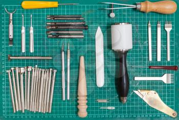 various tools for leathercraft on green self-healing mat