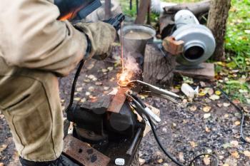 Welder welds buckle by point electric welding in outdoor rural workshop