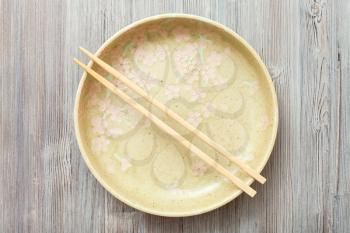 top view of one yellow green plate with chopsticks on gray brown table