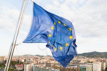 european union flag fluttering by wind above Barcelona city