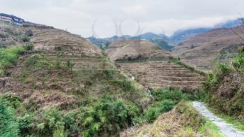 travel to China - pathway between terraced hills near Dazhai village in area of Longsheng Rice Terraces (Dragon's Backbone terrace, Longji Rice Terraces) in spring season