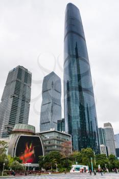 GUANGZHOU, CHINA - MARCH 31, 2017: tourists on square near towers in Zhujiang New Town of Guangzhou city in rainy day. Guangzhou is the third most-populous city in China with population about 13,5 mln