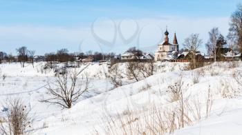 cityscape of Suzdal town with Holy Cross Exaltation and St Cosmas and St Damian Churches in Korovniki district on riverbank of frozen river in winter in Vladimir oblast of Russia