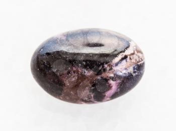 macro shooting of natural mineral rock specimen - polished Rhodonite gemstone on white marble background