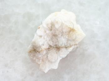 macro shooting of natural mineral rock specimen - scheelite vein (tungsten ore) in raw stone on white marble background