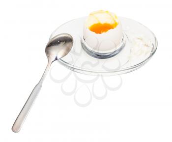 open soft-boiled white egg and spoon in glass egg cup isolated on white background