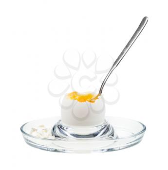 side view of open soft-boiled white egg with spoon in glass egg cup isolated on white background