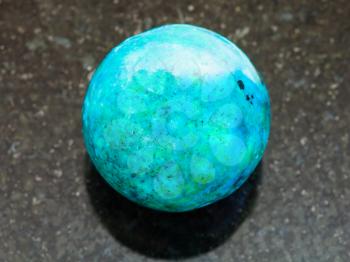macro shooting of natural mineral rock specimen - ball from Chrysocolla gemstone on dark granite background