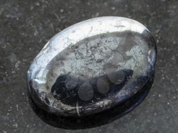 macro shooting of natural mineral rock specimen - cabochon from Hematite gemstone on dark granite background