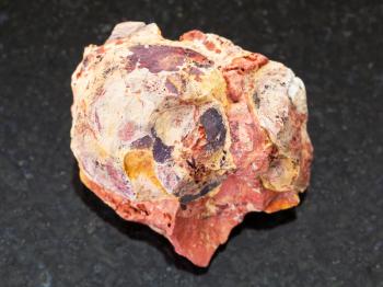 macro shooting of natural mineral rock specimen - raw Bauxite (aluminium ore) stone on dark granite background