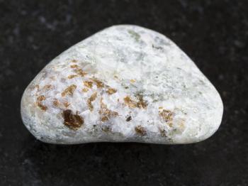 macro shooting of natural mineral rock specimen - brown chondrodite crystals in polished calcite stone on dark granite background from Pitkyaranta region of Karelia, Russia
