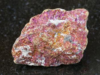 macro shooting of natural mineral rock specimen - rough red Chalcopyrite stone on dark granite background from Mexico
