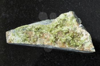 macro shooting of natural mineral rock specimen - raw crystal of green Vesuvianite gemstone on dark granite background from Bazhenovskoe mine, Sverdlovsk region, Ural Montains, Russia