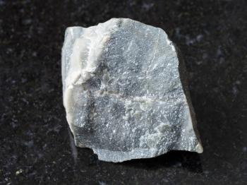 macro shooting of natural mineral rock specimen - raw Hornfels stone on dark granite background