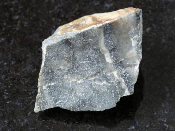 macro shooting of natural mineral rock specimen - rough hornstone stone on dark granite background