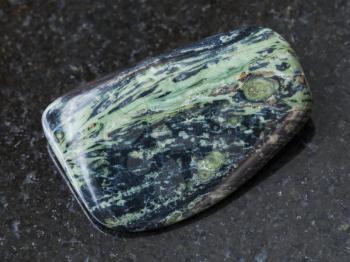 macro shooting of natural mineral rock specimen - polished rhyolite gemstone on dark granite background from Madagascar