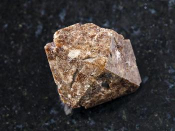 macro shooting of natural mineral rock specimen - raw crystal of Zircon gemstone on dark granite background from Marchenko Peak, Khibiny Mountains, Kola Peninsula, Russia