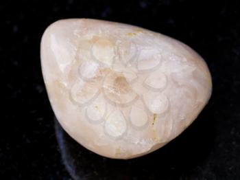 macro shooting of natural mineral rock specimen - tumbled Stilbite gemstone on dark granite background from India