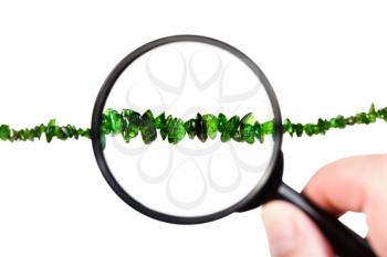 view of chrome diopside necklace through magnifier isolated on white background