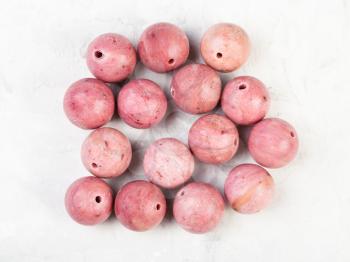 top view of beads from natural pink rhodonite gemstone on gray concrete background