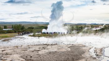 travel to Iceland - tourists near Strokkur geyser eruption in Haukadalur area in autumn