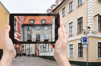 travel concept - tourist photographs house over Swedish Gate on Troksnu iela of Riga old town in Latvia in autumn on tablet