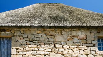 travel to France - stone wall and thatched roof of old country house in Brehat commune at Ile-de-Brehat island in Cotes-d'Armor department of Brittany in summer sunny day