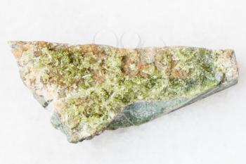 macro shooting of natural mineral rock specimen - raw crystal of green Vesuvianite gemstone on white marble background from Bazhenovskoe mine, Sverdlovsk region, Ural Montains, Russia