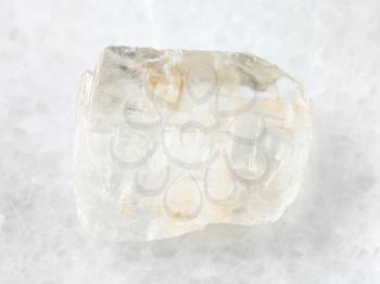 macro shooting of natural mineral rock specimen - rough crystal of Petalite gemstone on white marble background from Araguaia mine, Brazil