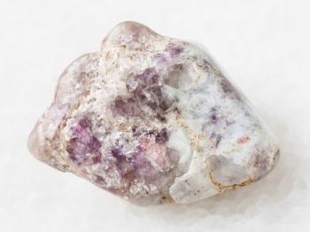 macro shooting of natural mineral rock specimen - pink Tourmaline crystas in Lepidolite mica in tumbled quartz stone on white marble background from Kalba mine, Kazakhstan