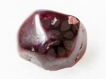 macro shooting of natural mineral rock specimen - polished red garnet gemstone on white marble background