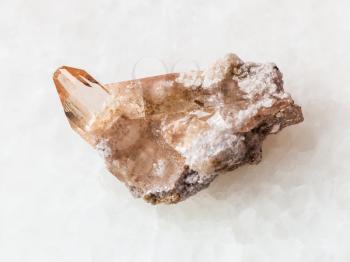 macro shooting of natural mineral rock specimen - rough crystal of topaz gemstone on white marble background from Brazil