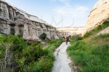 Travel to Turkey - tourist walks along pathway near Goreme town in Cappadocia in spring