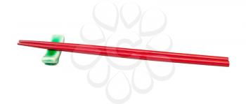 side view of red painted wooden chopsticks served on chopstick rest isolated on white background