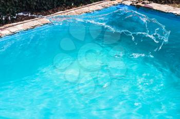splashing of disinfectant in outdoor swimming pool on backyard of country house