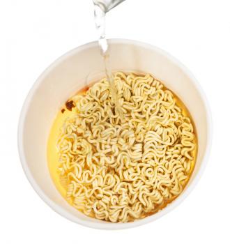 cooking instant noodles - water trickle flows in cup with dried instant noodles isolated on white background