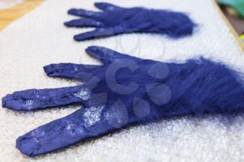 workshop of hand making a fleece gloves from blue Merino sheep wool using wet felting process - fibers close up covers back side of glove with cutting pattern